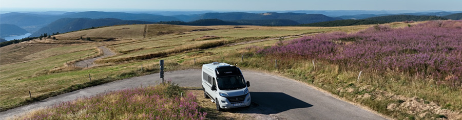 Fourgon aménagé circulant sur une route de montagne dans les Vosges, illustrant l'impact de la réglementation camping-car 2025 sur les itinéraires en zone naturelle