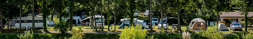 Photo d'un camping ombragé, avec caravanes, camping-cars et tentes